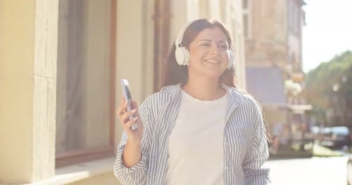 Cheerful Woman Listening to Music on City Sidewalk