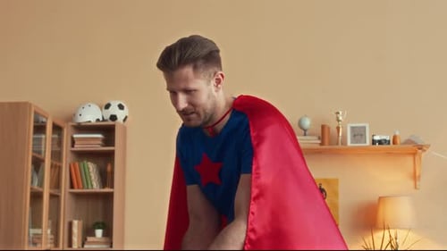 Father Pushing Son in Superhero Costume on Chair