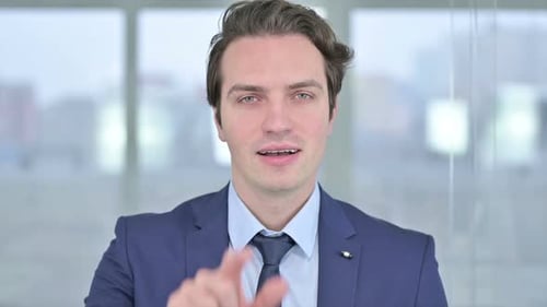Portrait of Young Businessman Pointing Finger and Inviting