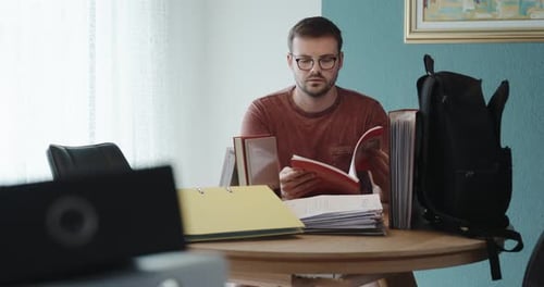 Konzentrierter Mann, der im Home Office mit Akten und Laptop studiert