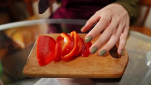 Woman Slicing Vibrant Red Bell Pepper With Knife