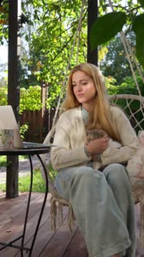 Woman with Cat Works on Laptop Outdoors