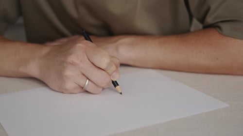 Man Drawing on Paper with Pencil Close Up