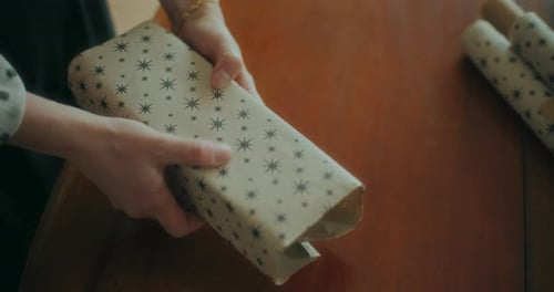 Hands Wrapping a Gift on a Table