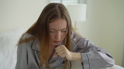 Une
belle fille malade caucasienne en pyjama se lève du sommeil dans la chambre.