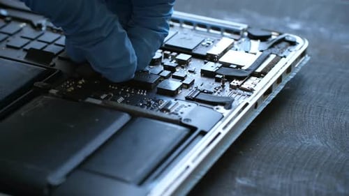 Gloved Hand Connects Ribbon Connector on Laptop