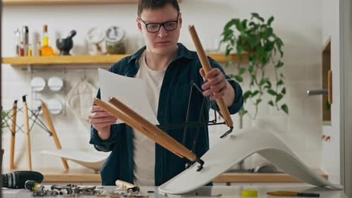 Un charpentier blanc étudie les instructions d'assemblage de meubles tout en assemblant une chaise en privé