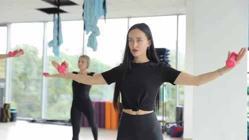 Young Women in the Gym are Working Out with Dumbbells