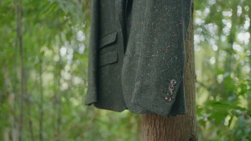Groom jacket hanging on tree branch outdoor wedding preparation scene