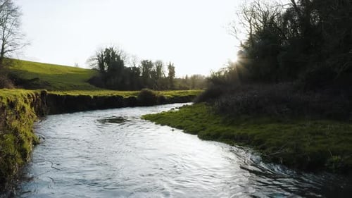 Flying close to the water with the sun coming out from behind the trees. The sky is clear and it's a