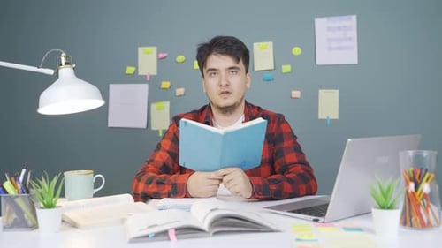 Young Adult Studying at Desk with Laptop and Books