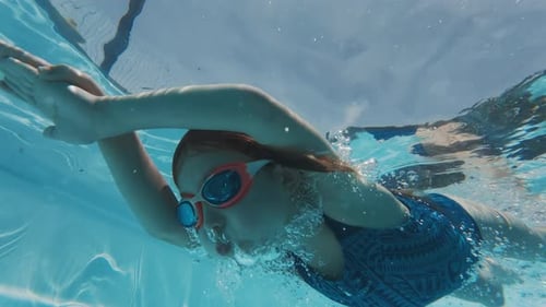 Girl swims underwater in the pool. Pre teen girl feels herself comfortable and relaxed underwater.