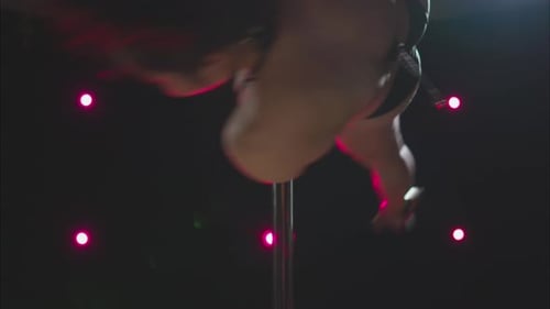 Girl doing a pole routine on a dark stage