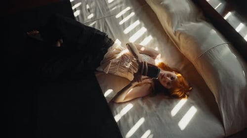 Woman Lies on Bed Using Cell Phone