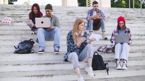 Multiracial Students Engaged in Group Study Session on Outdoor Steps in a Sunny Park Utilizing