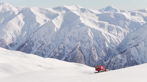 Aerial View of Snowcat Grooming Slopes in Mountain Landscape