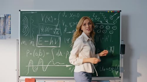 Woman Writes Equations on Chalkboard in Classroom
