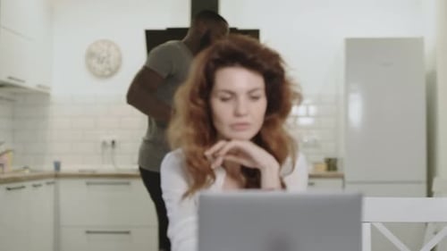 Couple Laughing and Drinking Coffee While Looking at Laptop