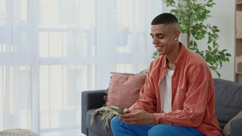 Young Adult Relaxing on Couch Using Smartphone