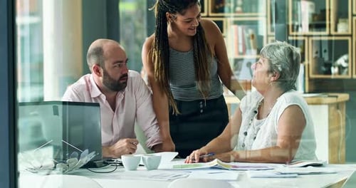 4k video footage of a diverse group of colleagues talking together over paperwork in an office