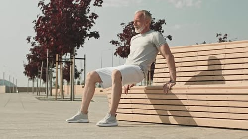 Active Senior Man Doing Triceps Dips by Street Bench Outdoors