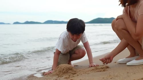 Mother and asian son playing sand on the beach together having fun enjoy freedom