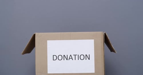 Two people packing clothes in a donation box