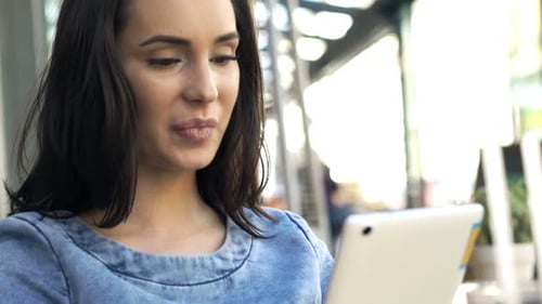Young Attractive Woman with Tablet Sitting in Cafe in City 20s