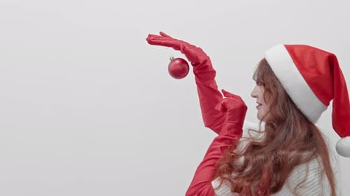 Woman in Santa Hat Smiles Holding Christmas Ornament