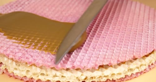 Kondensmilch mit einem Messer auf einen Waffelkuchen auftragen und ein süßes Dessert zubereiten