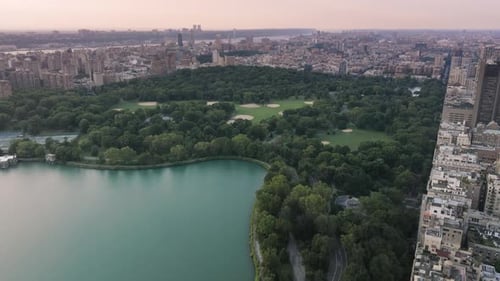 Beautiful Lake Surrounded By Green Park and Buildings of Manhattan Uptown in NYC