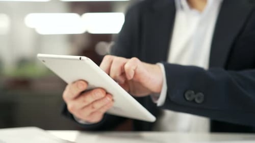 Close up of male hands holding digital tablet at desk at workplace in business office. Businessman