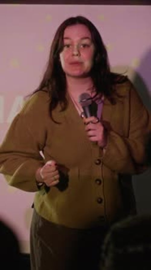 Young Woman Giving Presentation with Microphone on Stage