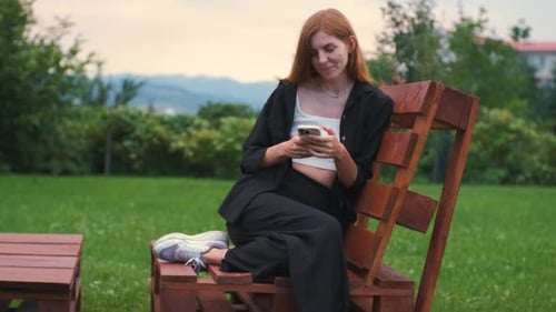 Beautiful Young Woman Enjoying the Sunset in Her Garden and Communicating on the Internet on a