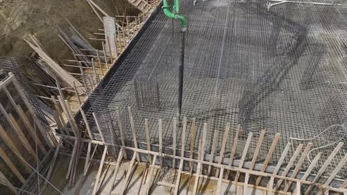 Aerial View Workers Laying Concrete for Building Foundation at Construction Site