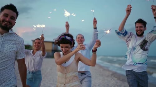 Multiethnic Friends Walking Dancing Having Fun on Night Party at Seaside with Sparklers Lights in