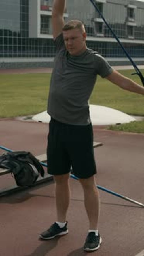 Male Javelin Thrower with Disability Warming up with Elastic Band at Stadium