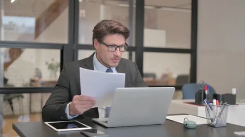 Man Working in Office With Documents and Laptop