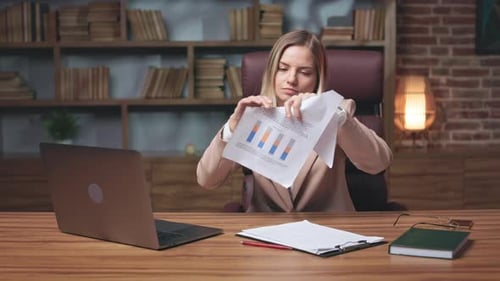 Empresaria enojada rasgando papeles y mirando a la cámara