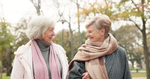 Senior, women and friends in a park bond, walking and enjoying conversation outdoor together