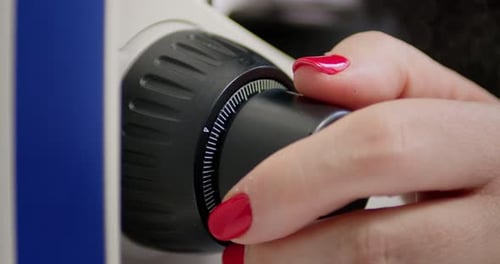 Close-Up of Hands Adjusting Modern Microscope in Laboratory