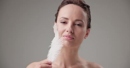 Woman Holding White Feather to Face