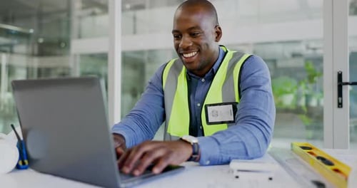 Smiling Man Works at Laptop in Bright Office