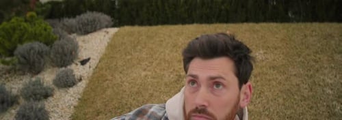 Young Man Waking Up in Morning Lying on Grass in Park After Sleepless Night Hangover On Background