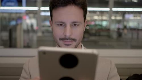 A Businessman Uses a Tablet in an Airport Lounge Blending Technology and Business Travel