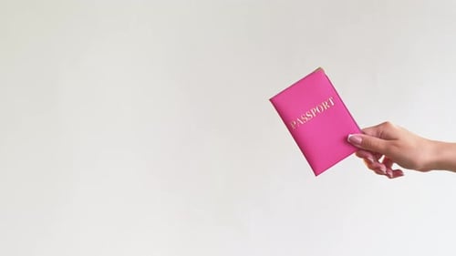 Hand Holding a Pink Passport Against White Background