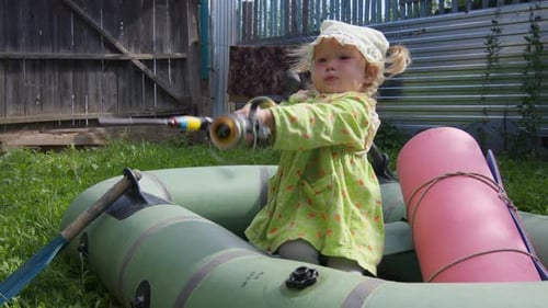 Garota brinca de pescar no quintal. Menina segura uma vara de pescar e se senta no barco situado
no verde