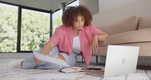 Woman Reviews Documents and Uses Laptop at Home