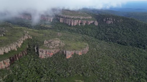 Jagged escarpment erosion, flyover rugged jungle cliffs through cloud