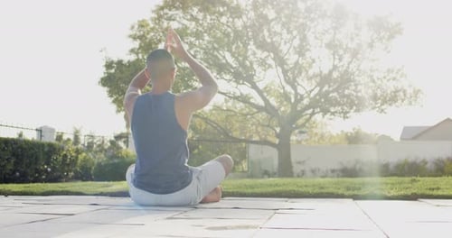 Focused biracial man practicing yoga in sunny garden, slow motion